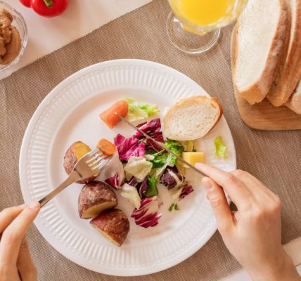 Top view of a nutritious breakfast setup with salad, bread, and fresh juice, perfect for a healthy start.