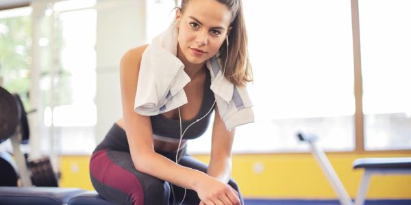 A fit woman in activewear rests on a bench between workouts at the gym.